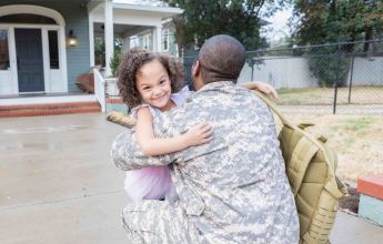 Veteran hugging daughter in front of new house while asking, am I eligible for a VA loan?